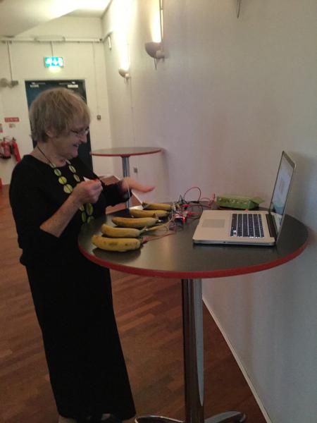 Professor Norma Rains trying out a banana piano created using a MaKey Makey toolkit as an example of multimodal interaction.