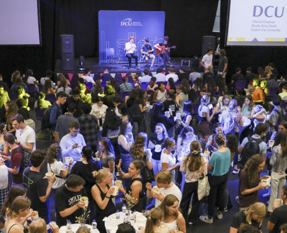 A group of people in a room with a stage and band