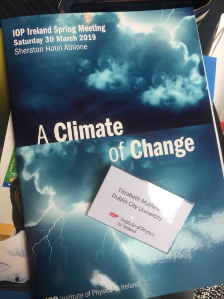 Image of a conference programme entitled A Climate of Change featuring an image of a storm. On top, there is a conference name badge for Elizabeth Mathews, Dublin City University