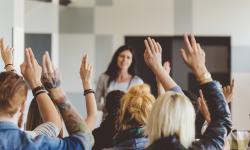 A group with raised hands at a seminar or conference.