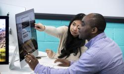 Picture of two students ( male and felmale) looking at a computer screen with the female student pointing at the screen