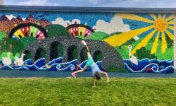 A student cartwheels in front of a mural