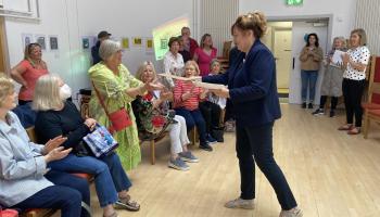 Coordinator hands award certificate to participant.
