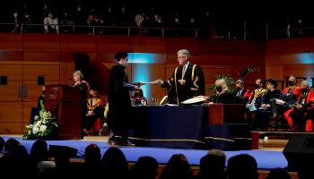 Graduate walks across the stage in O'Mahony Hall in the Helix