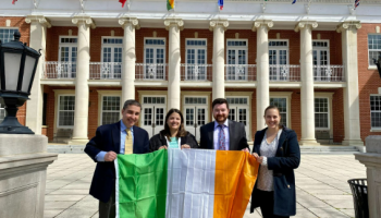 two men and two women in front of a building holding an Irish flag