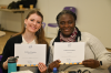 2 participants of the PPN Summer School holding their certificates up while posing 