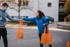 A Student Ambassador handing out orange DCU tote bags to a prospective student