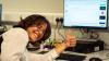 Student smiles beside computer