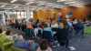 Shows a seat audience facing a speaker at a lectern