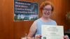 Shows a woman holding a certificate