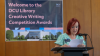 Shows a woman reading from a lectern