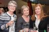 Three women smiling and posing for the camera, with champagne flutes in their hands