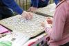 people assembling a jigsaw puzzle 