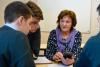 Three young men are gathered around an older woman who has her cellphone out and is looking at them