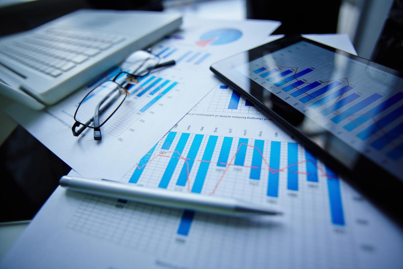 Graphs on paper beside a laptop