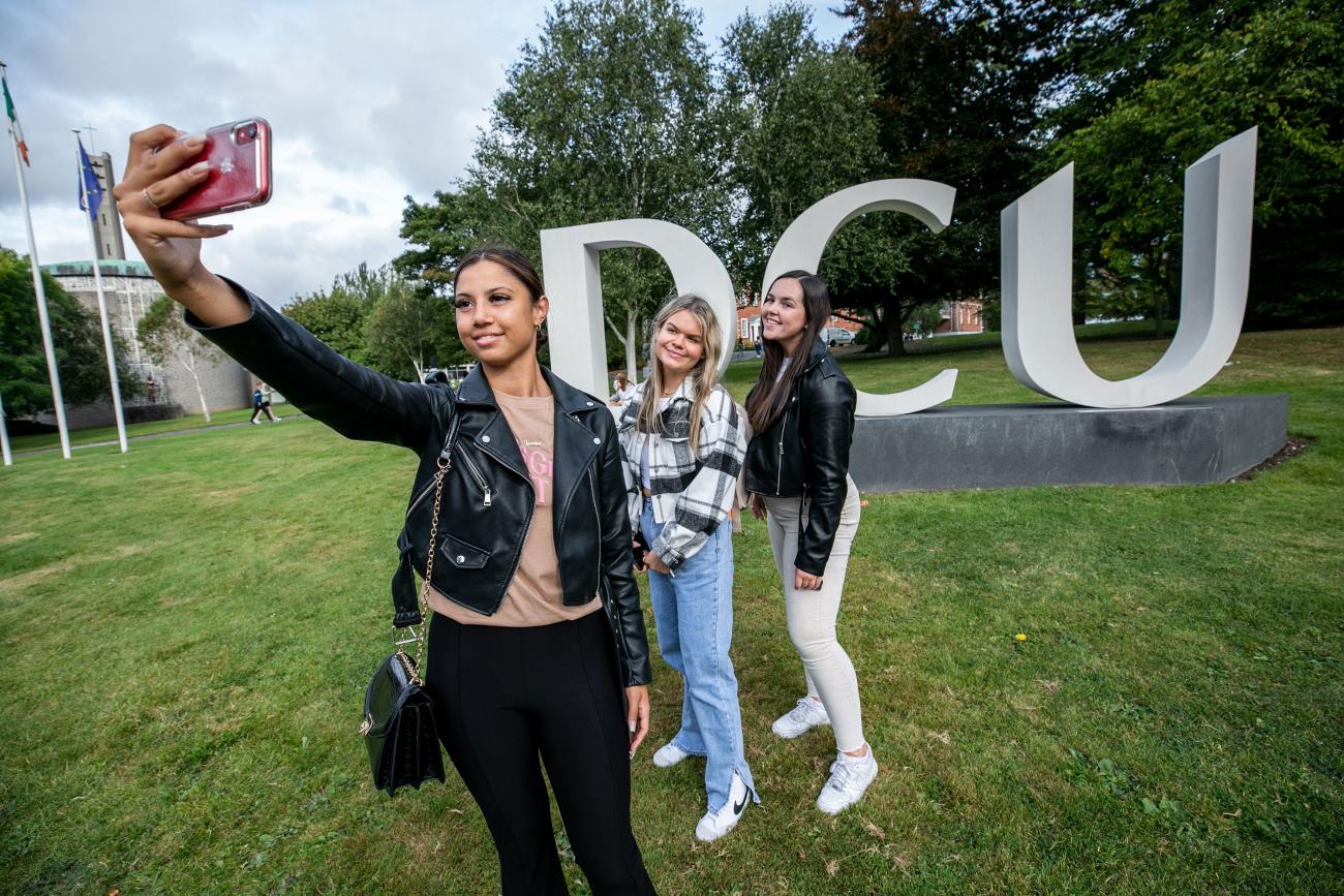 Students taking selfie by DCU sign