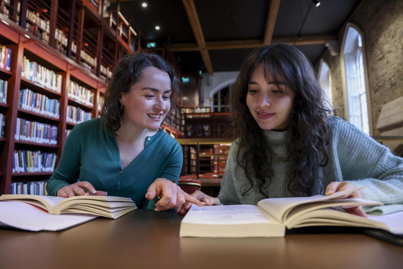 Students sitting at desk, table over open books