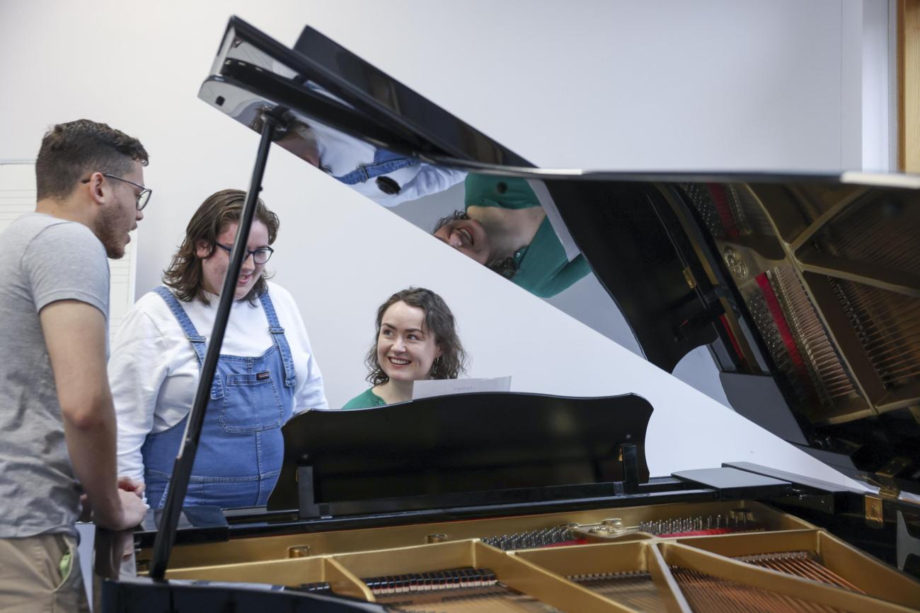 Students chatting around a piano