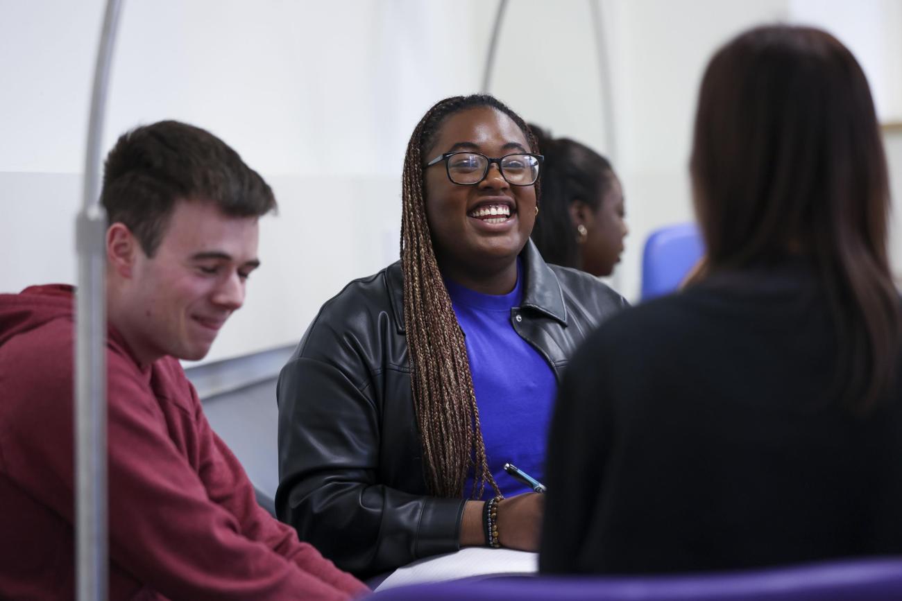 3 students chatting around a table
