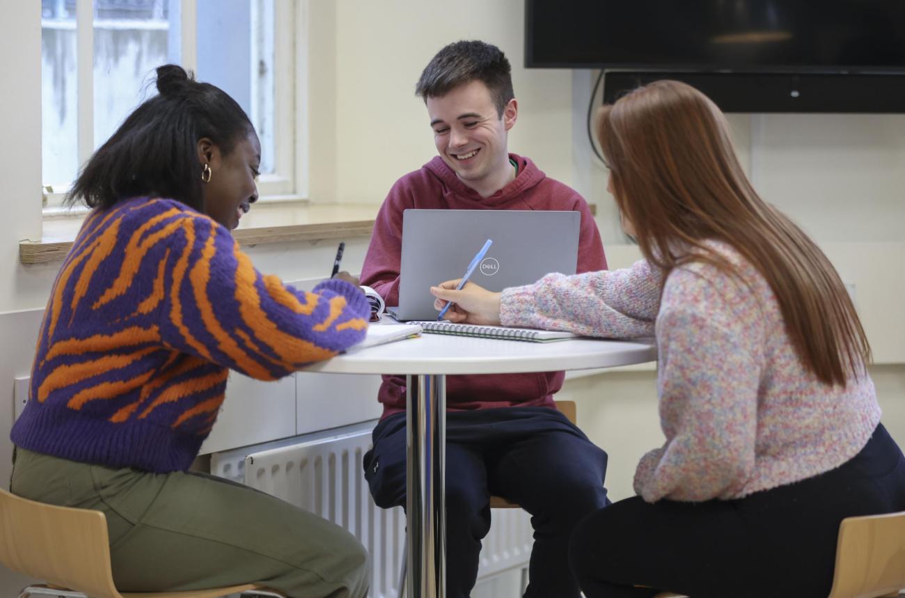 3 students chatting around a table