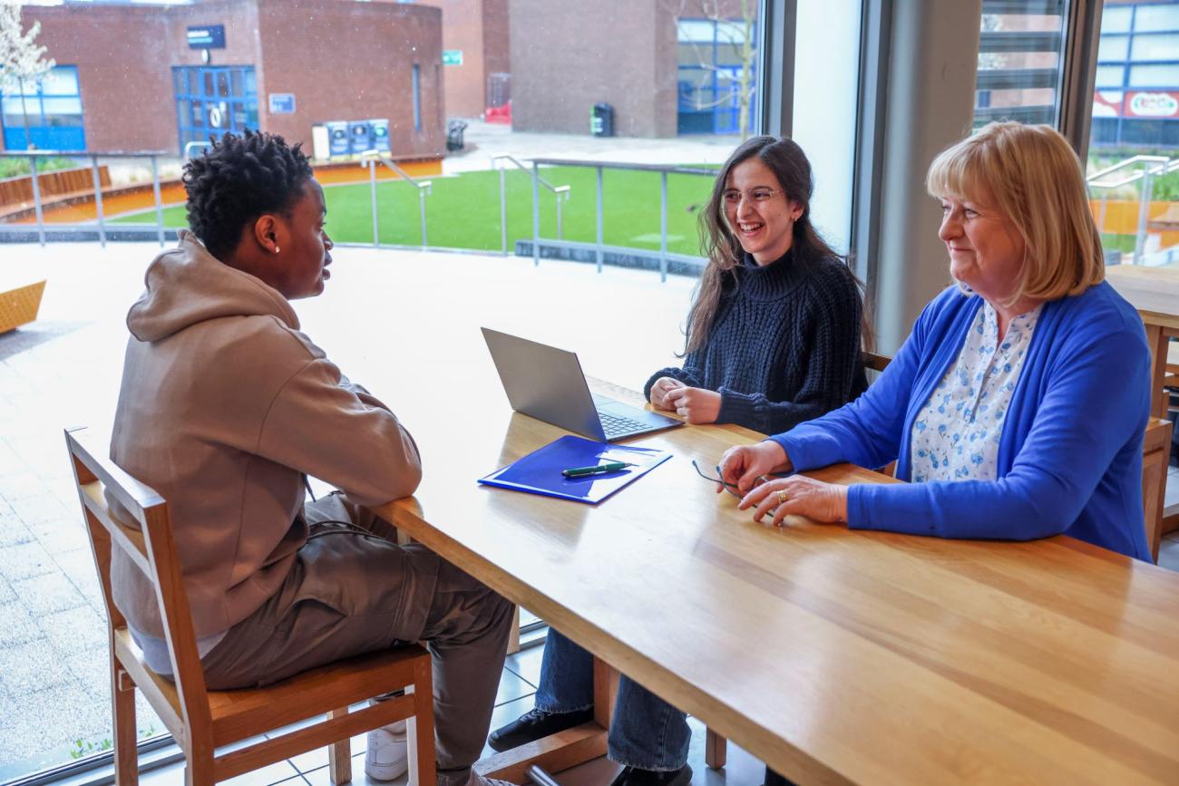 Students and staff talking around a table