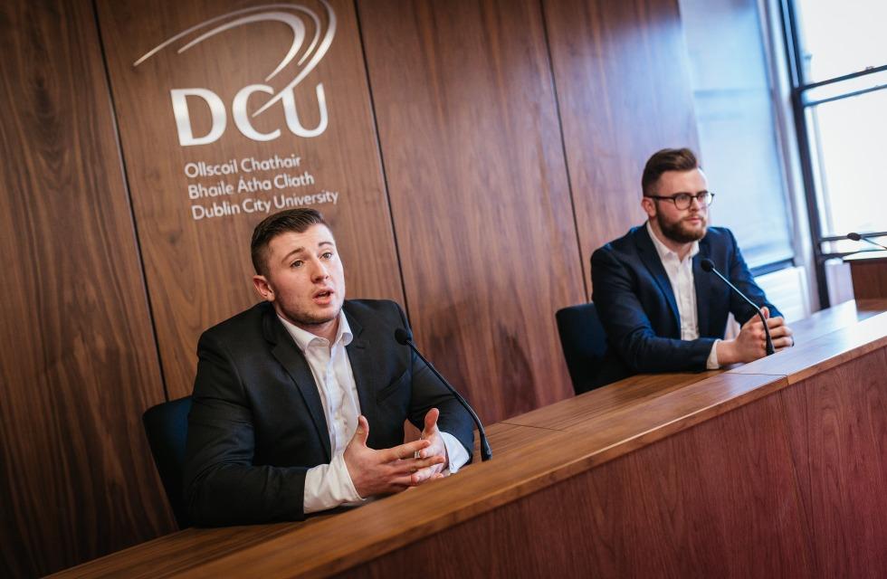 This image shows two male students in the moot courtroom