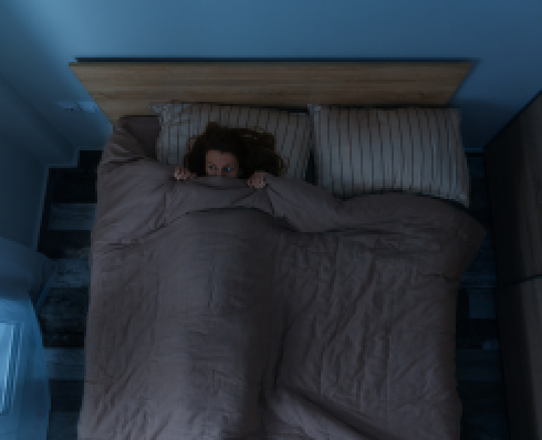 Shows a women in bed with the covers pulled up to her eyes