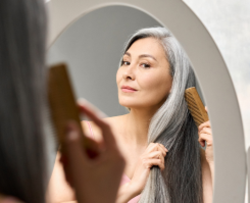 Shows a woman brushing her grey hair