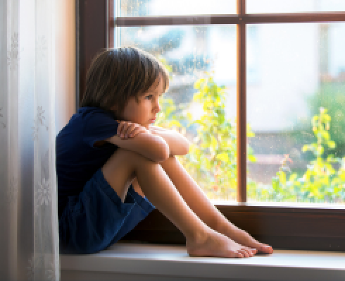 Shows a young boy sitting at a window