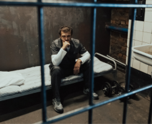 Shows a man sitting in a prison cell