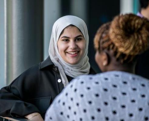 Image shows a student talking to another student