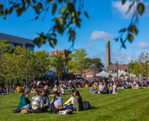 Students sit on the grass on campus