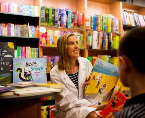 Woman dressed as doctor holds up childrens book 