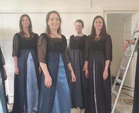 Female Choir members standing wearing blue and navy dresses 
