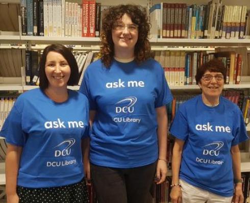 3 library staff wearing 'ask me' t-shirts
