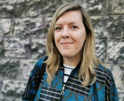 Artist Susan Leen stands in front of brick wall