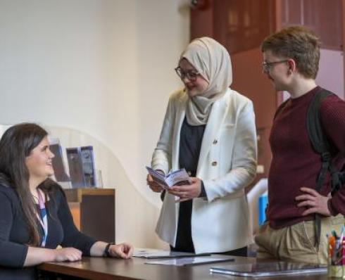 students and library staff member at the help desk 