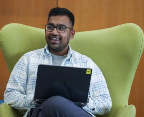 Happy student sitting in Vibrant green chair with a laptop