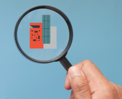 Fingers holding a magnifying glass which is above a graphic of a red, blue and grey building