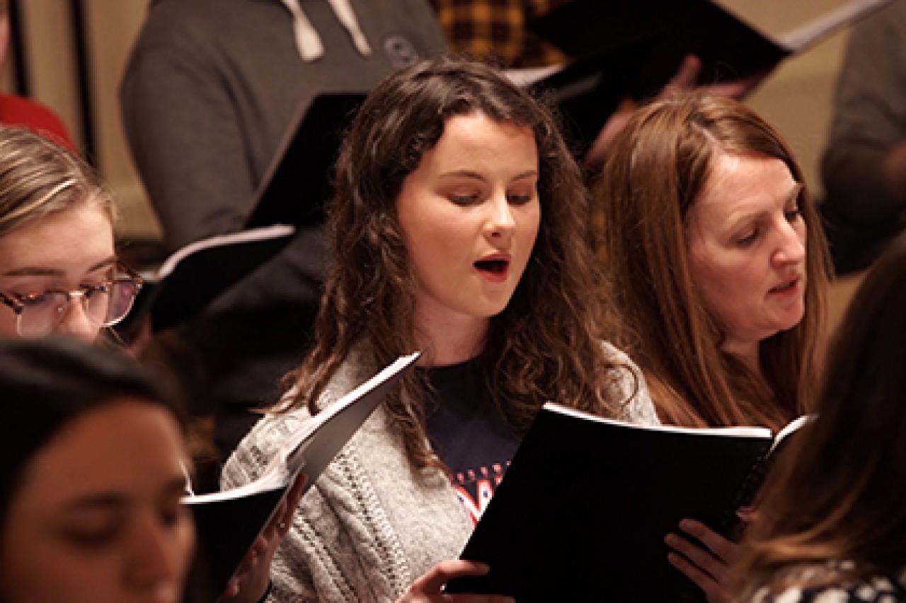 Image of a choice singing, a women with curly hair focussed and singling.