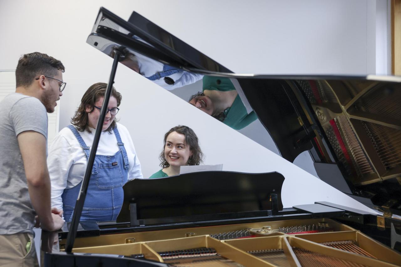 Students chatting around a piano