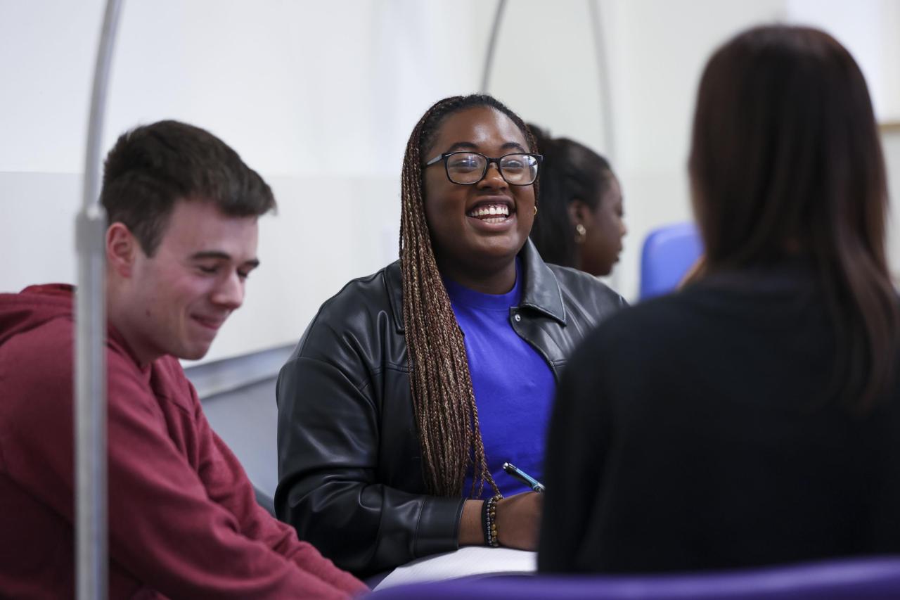 3 students chatting around a table