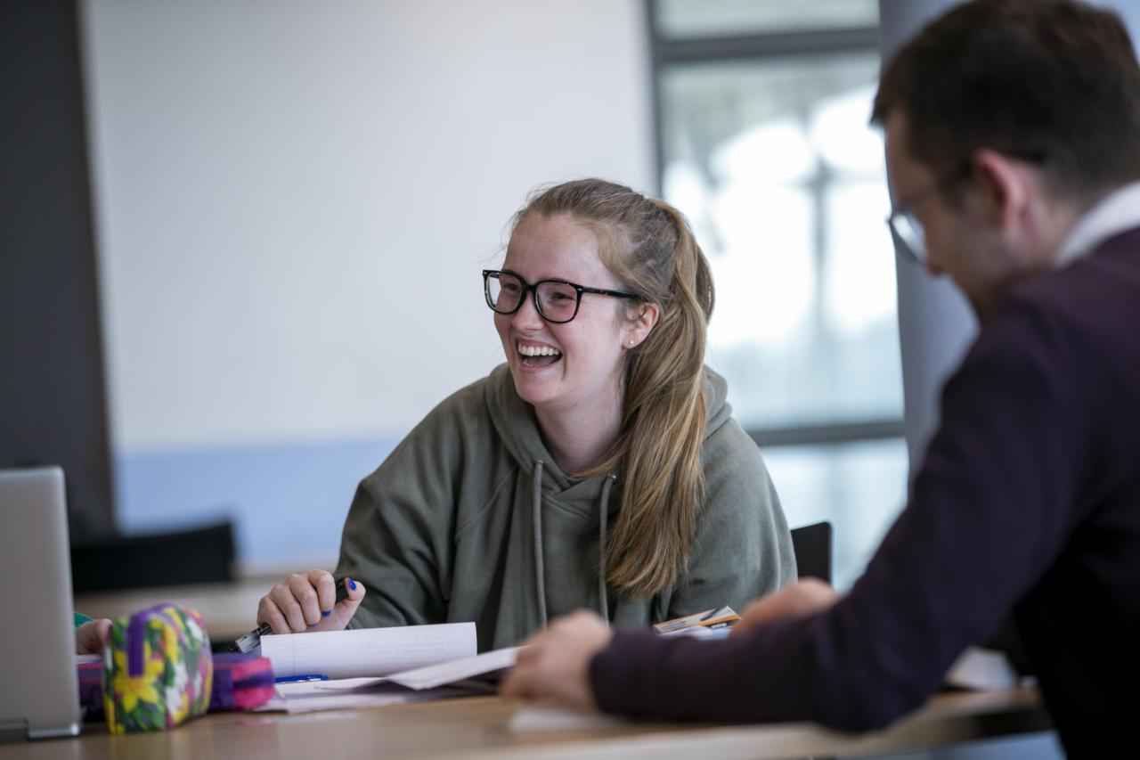 A smiling student in class sitting at a desk