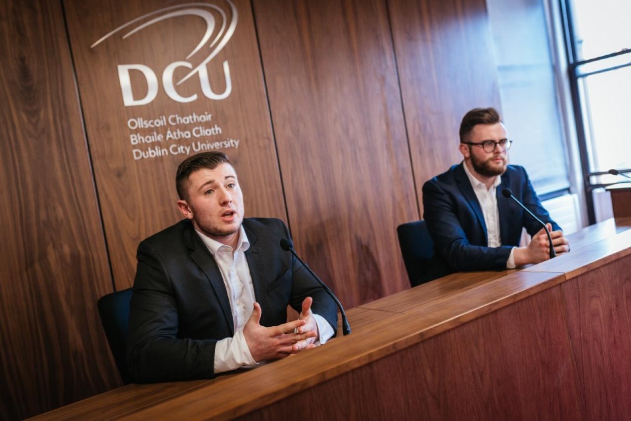 This image shows two male students in the moot courtroom