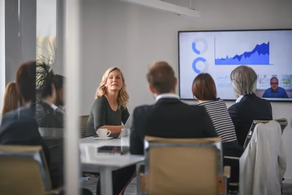 Shows woman in boardroom leading meeting