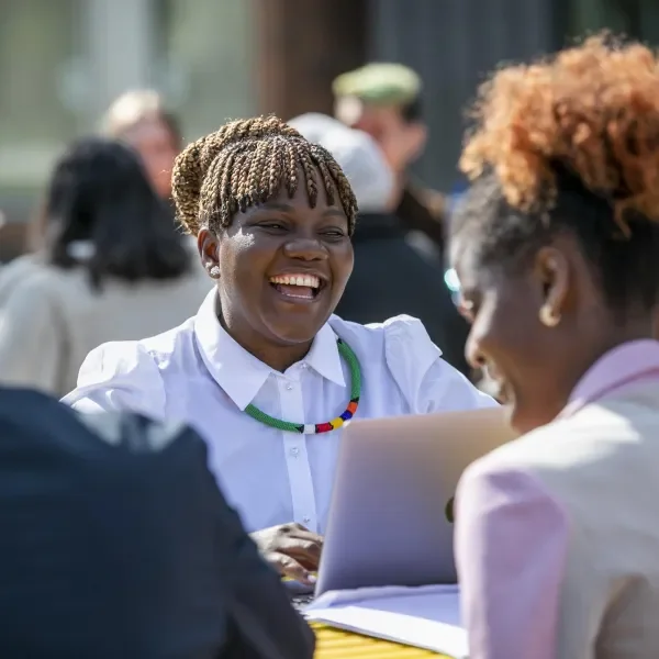 A photo of some international students sitting in the sun chatting and laughing to each other.
