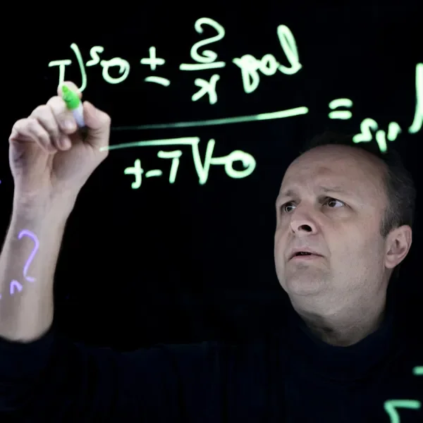 Researcher writing maths on blackboard