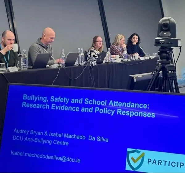 Researchers on a panel with a laptop reading the title of the presentation 