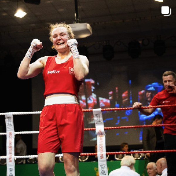 Shows member of DCU boxing celebrating her victory in boxing ring