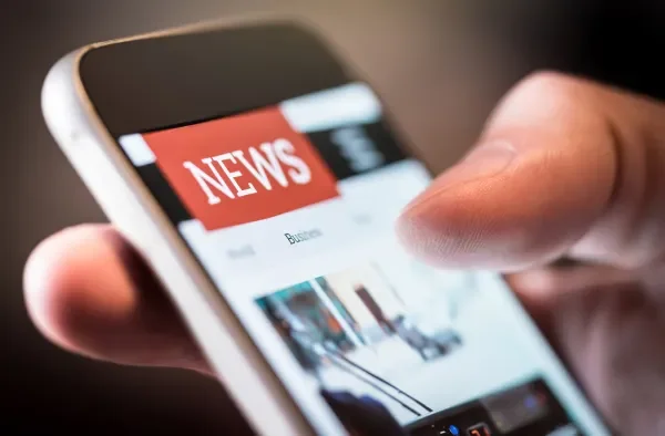 A person scrolls on a news site on their phone.